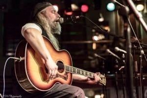A man sitting down playing a guitar